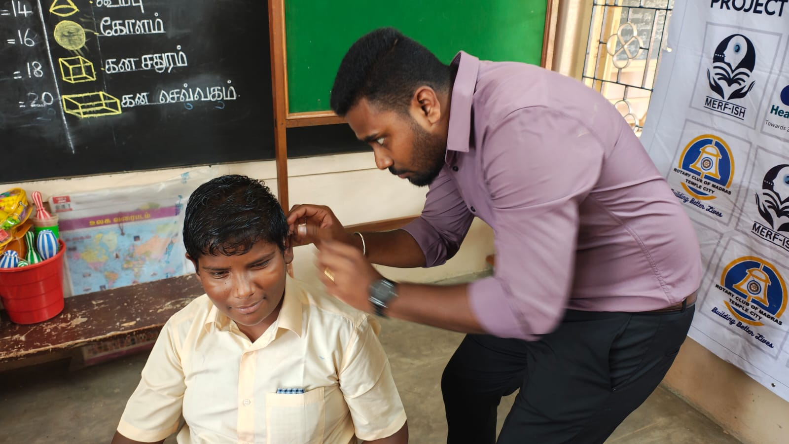 Audiologist fitting hearing aid for a student at Dolours School